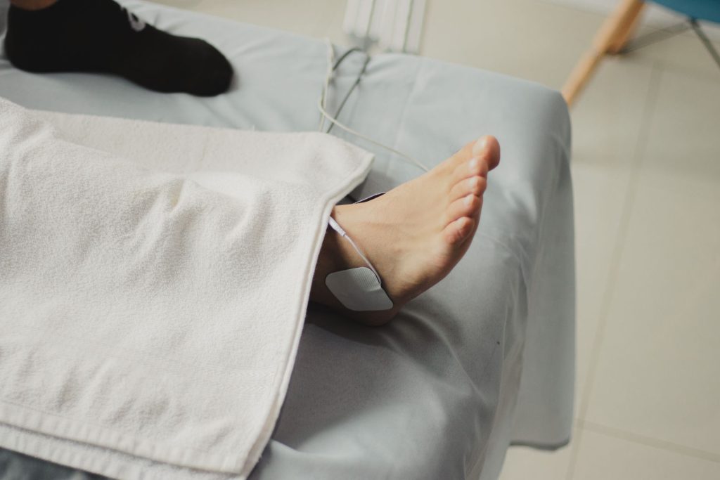 Fuß einer Patientin wird fürsorglich auf der Behandlungsliege versorgt