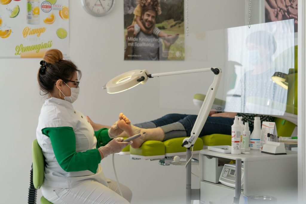 Podologin behandelt konzentriert den Fuß einer Patientin auf der Behandlungsliege