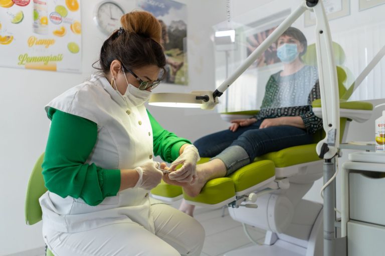 Podologin führt eine podologische Behandlung am Fuß einer Patientin durch
